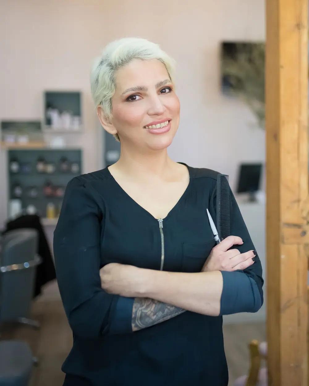 Profissional de salão de beleza sorridente, de braços cruzados