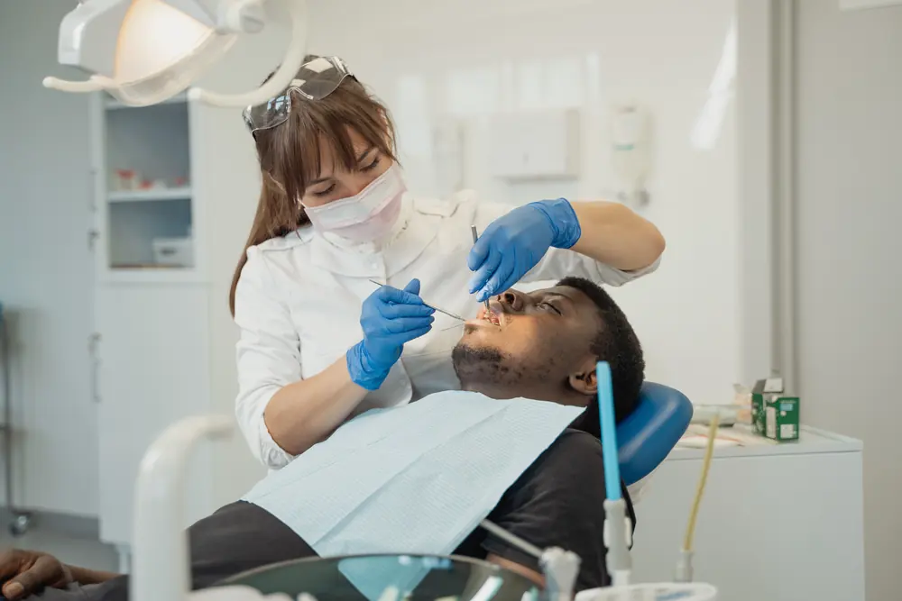 Dentista examina um paciente na cadeira odontológica em um consultório claro