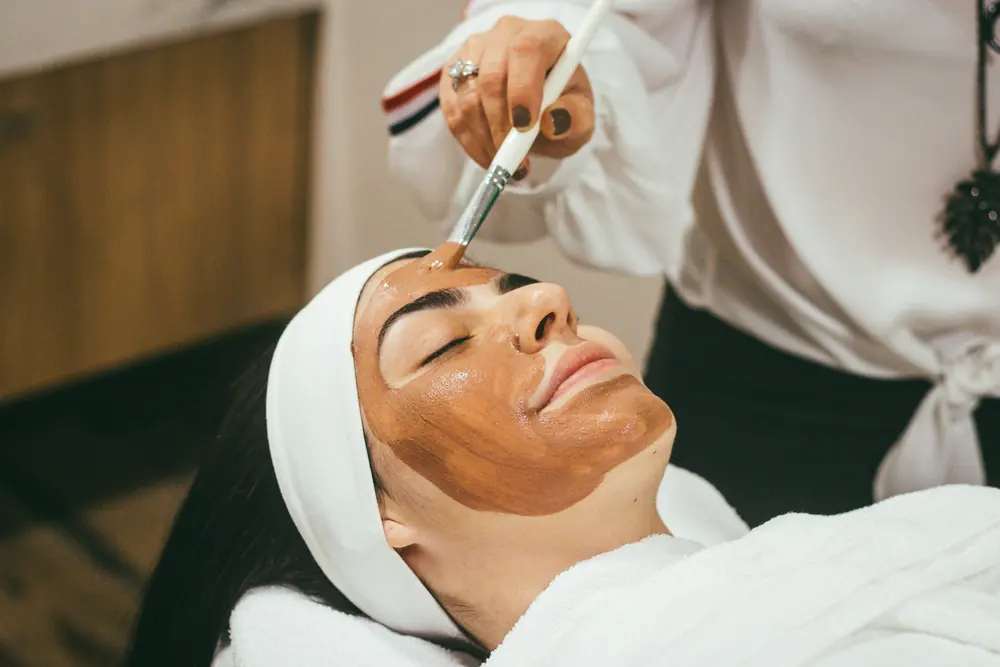 Esteticista aplica máscara facial em uma cliente em uma clínica de estética